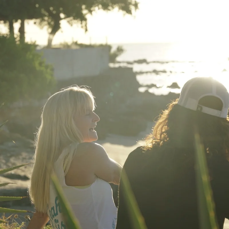 Joss Alabi and a guest looking out at the ocean together in the evening light