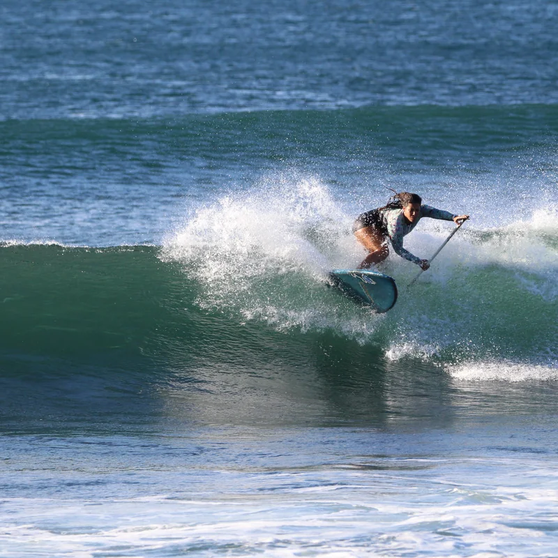 A paddle surfer riding along the face of a clean wave in El Salvador