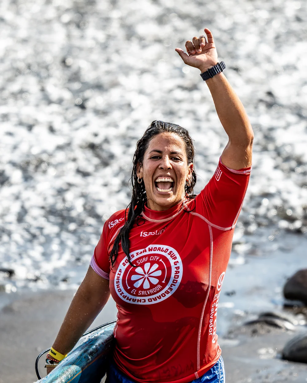 Joss Alabi coming out of the water in an ISA World Championship jersey with her fist raised