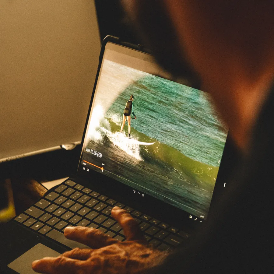 A retreat guest reviewing her surf session on a laptop, frame by frame